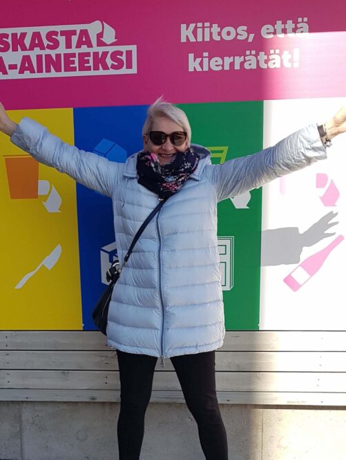 nainen punaisessa paidassa istuu valkoinen koira sylissä